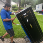 Blue Ox movers moving a gun safe on a dolly across a lawn